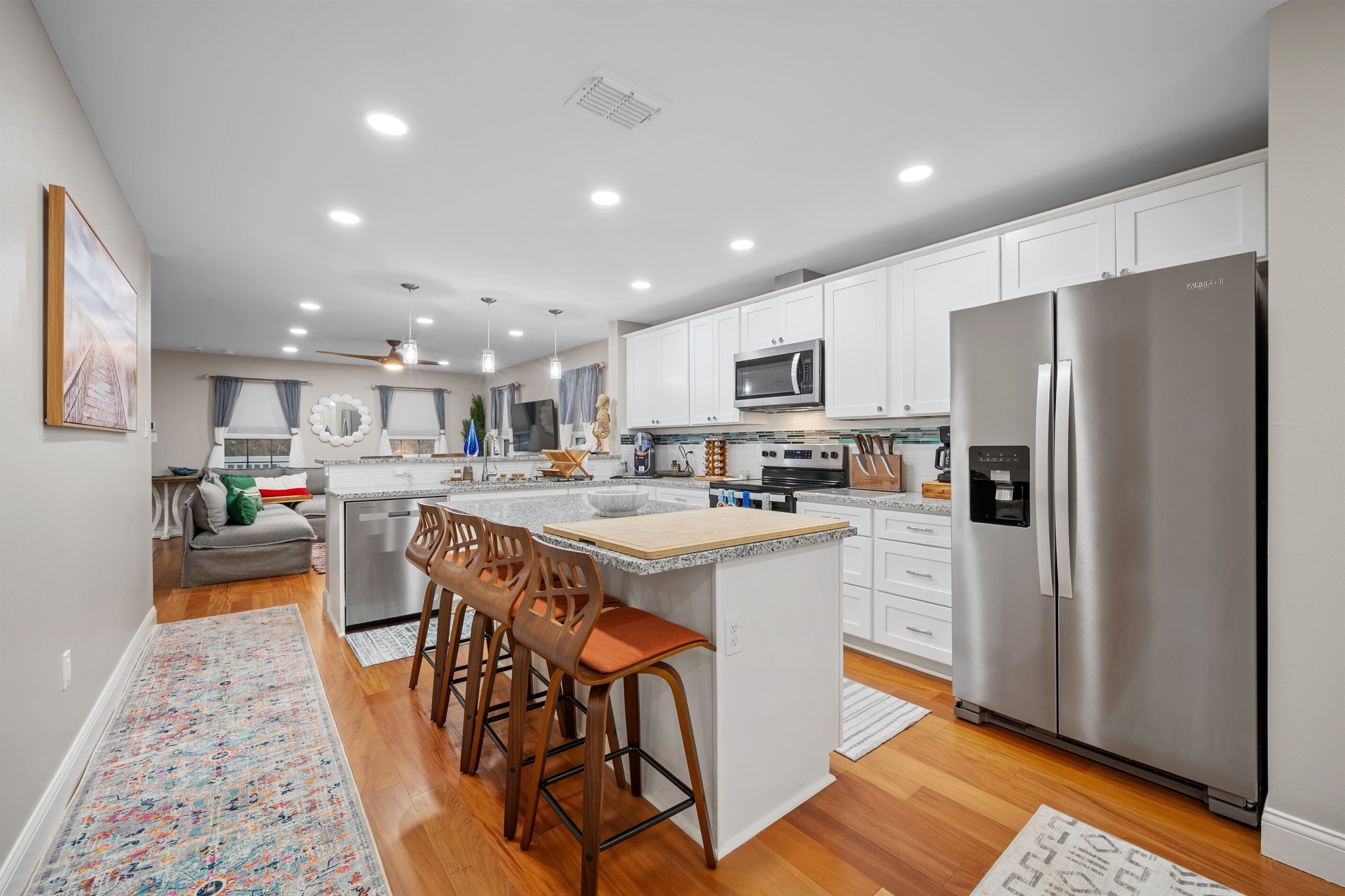 A modern kitchen with white cabinets, stainless steel appliances, and a central island with bar stools.