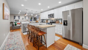 A modern kitchen with white cabinets, stainless steel appliances, and a central island with bar stools.