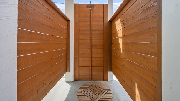 A narrow wooden corridor with a central door and a patterned mat on the floor.