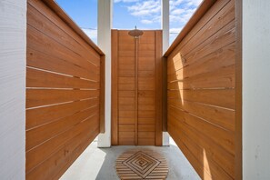 A narrow wooden corridor with a central door and a patterned mat on the floor.
