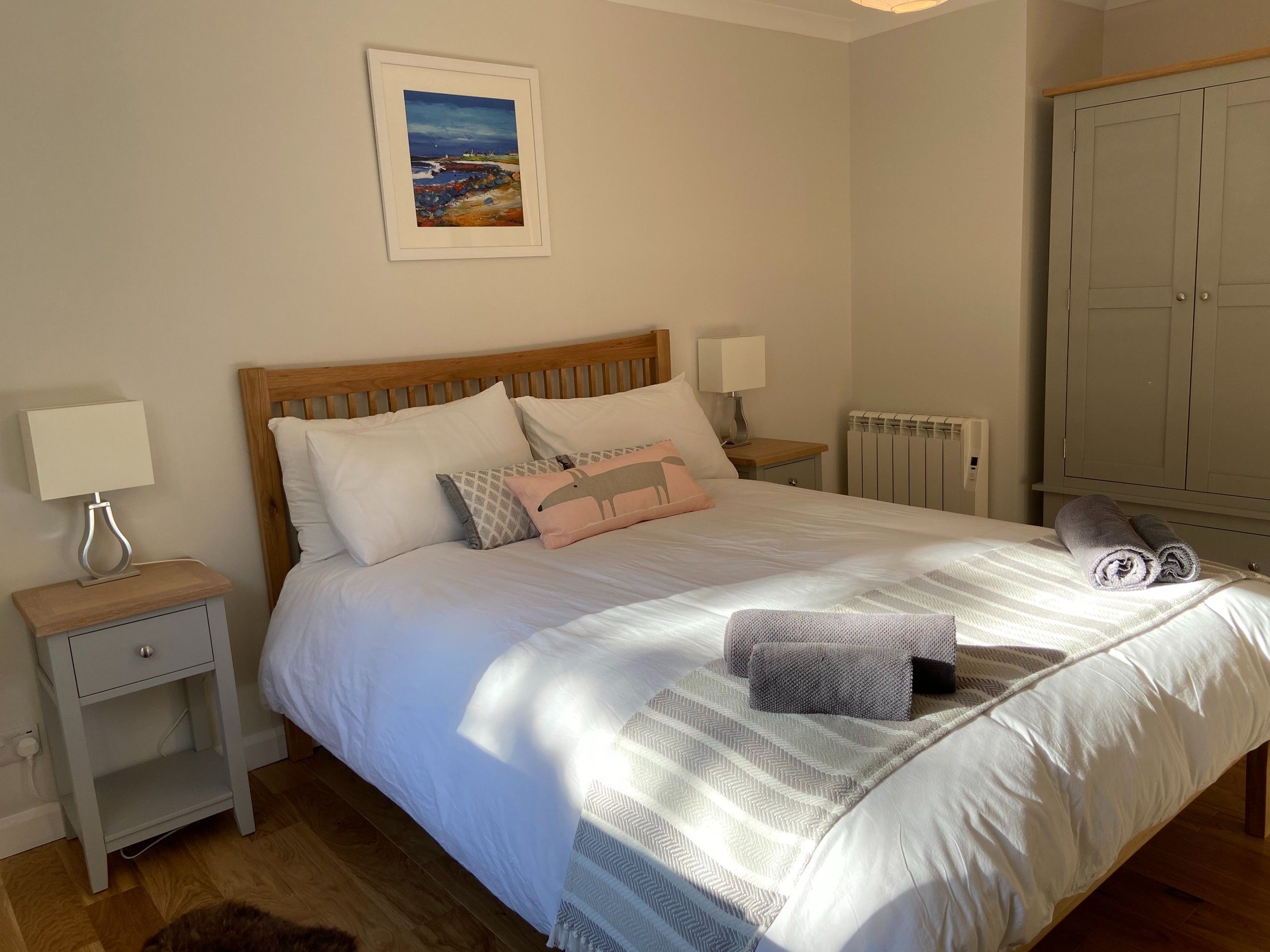 A neatly made bed with a striped blanket, a wooden headboard, and a nightstand with a lamp.
