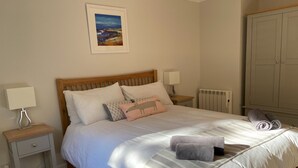 A neatly made bed with a striped blanket, a wooden headboard, and a nightstand with a lamp. - Mallard - sleeps 6 guests in 3 bedrooms (Boat of Garten)