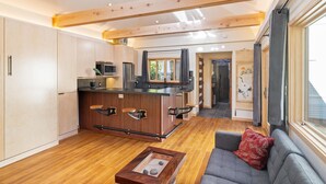 A modern kitchen with a central island, wooden beams, and a large window.