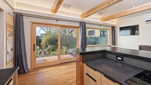 A modern kitchen with wooden beams, a large sliding glass door, and a black countertop.