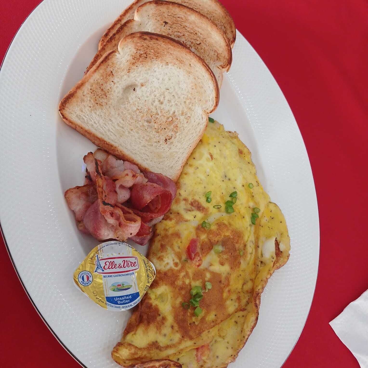 A plate with toast, bacon, and an omelette.