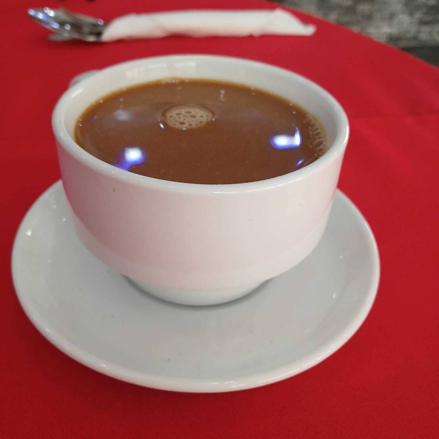 Una taza de café blanco sobre un platito blanco.