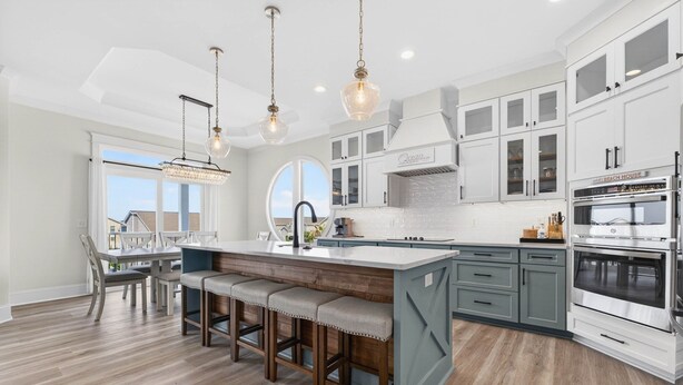 A modern kitchen with a central island, bar stools, pendant lighting, and a large window. - Brand New 7 Bedroom, 7 Bathroom Beach House (Ocean Isle Beach)