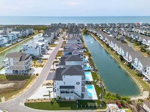 A coastal residential area with multiple-story houses, a marina, and a clear view of the ocean.