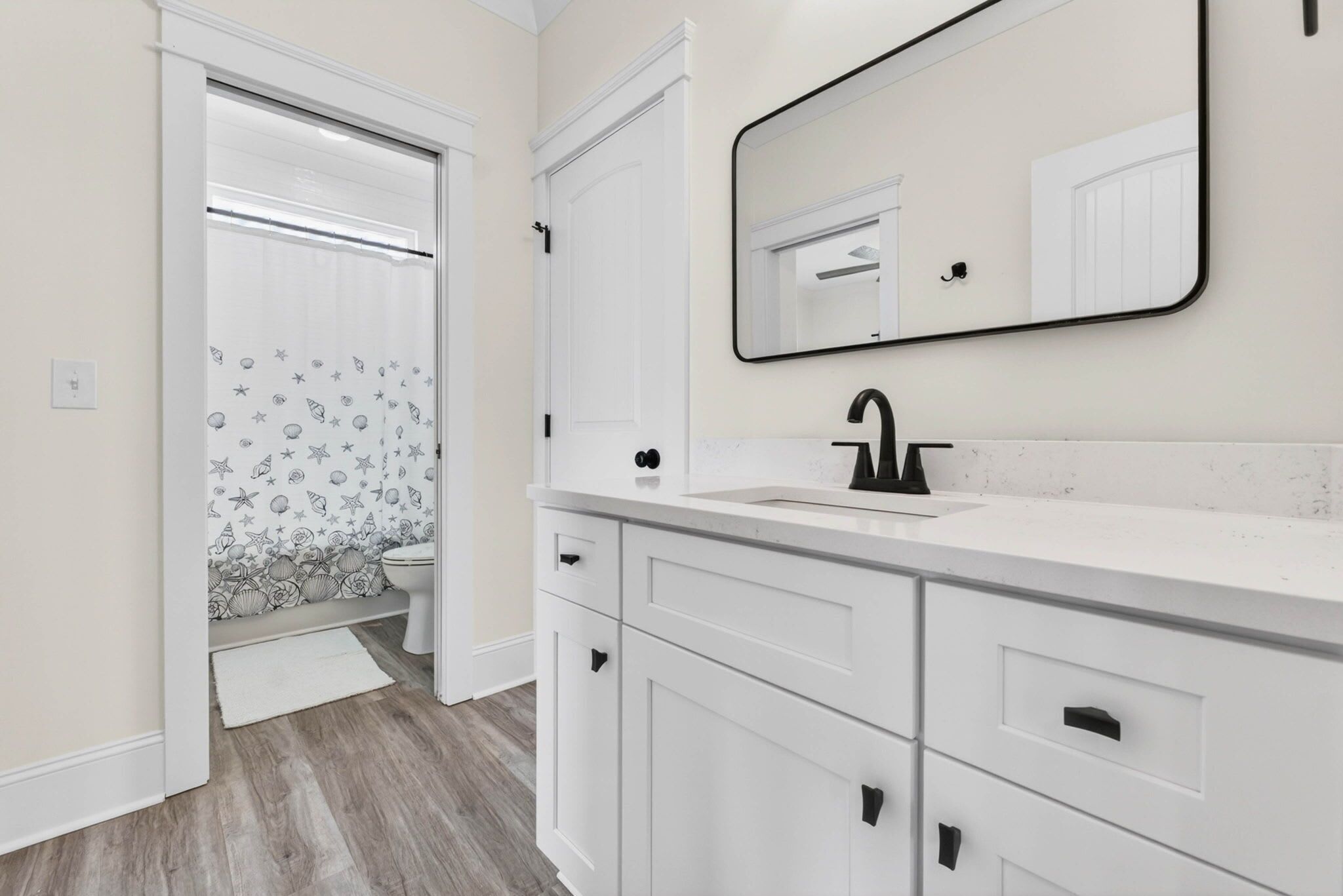 A bathroom with white cabinetry, a black sink, and a mirror.