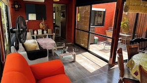 Una sala de estar moderna con un sofá, un ventilador y una mesa. Se ve un patio exterior.