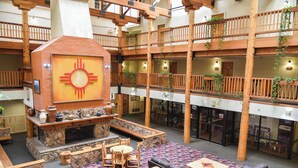 A spacious lobby with a central fireplace, multiple seating areas, and a balcony with wooden railings. - Lift's West #105 - Cozy Corner at the Lifts (Red River)