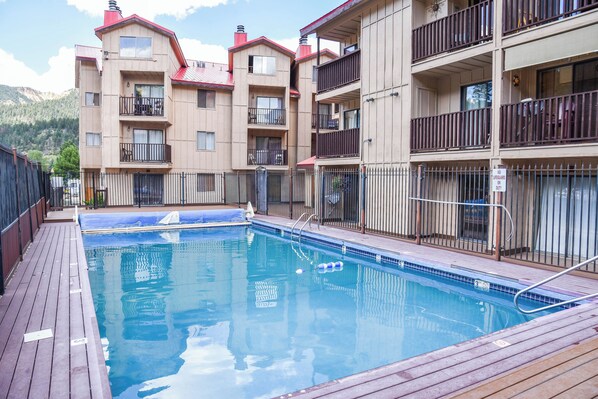 Una piscina con muelle de madera, rodeada de edificios de varios pisos con balcones.