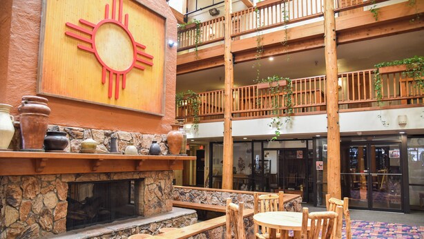 A multi-level wooden balcony with stone walls, a fireplace, and wooden furniture. - Lift's West #105 - Cozy Corner at the Lifts (Red River)
