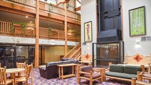 A spacious lobby with a high ceiling, wooden furniture, a patterned carpet, and a staircase leading to an upper floor. - Lift's West #105 - Cozy Corner at the Lifts (Red River)