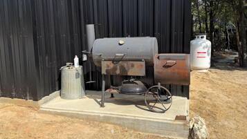 Una parrilla de gas portátil con tanque de metal, cilindro de propano y cuerpo de metal.
