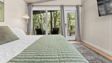 Un dormitorio con cama, ventana, una silla y vistas a árboles.