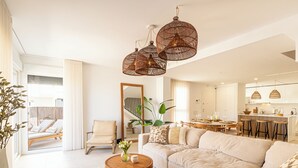 Un salon spacieux avec un grand canapé, une table basse et un coin repas, la cuisine étant située à l’arrière-plan.