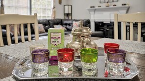 Una bandeja con bolsitas de té, una tetera de plata y vasos de colores sobre una mesa en un salón.