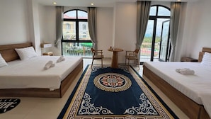 Una habitación de hotel con dos camas, una mesita y vistas al exterior.