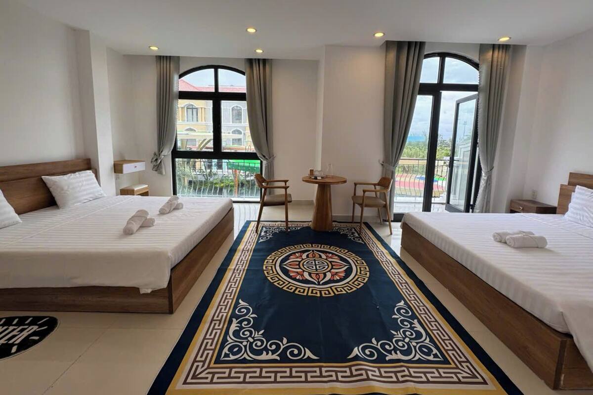 Ein Hotelzimmer mit zwei Betten, einem kleinen Tisch und Blick ins Freie.
