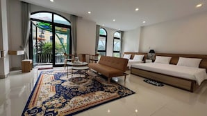 Una habitación de hotel espaciosa con una cama grande, un sofá, una mesa de centro y una alfombra estampada.