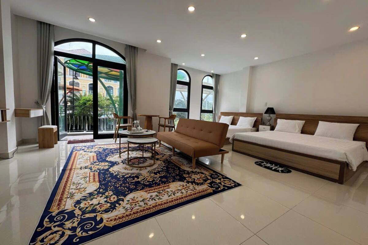 Ein geräumiges Hotelzimmer mit einem großen Bett, einem Sofa, einem Couchtisch und einem gemusterten Teppich.