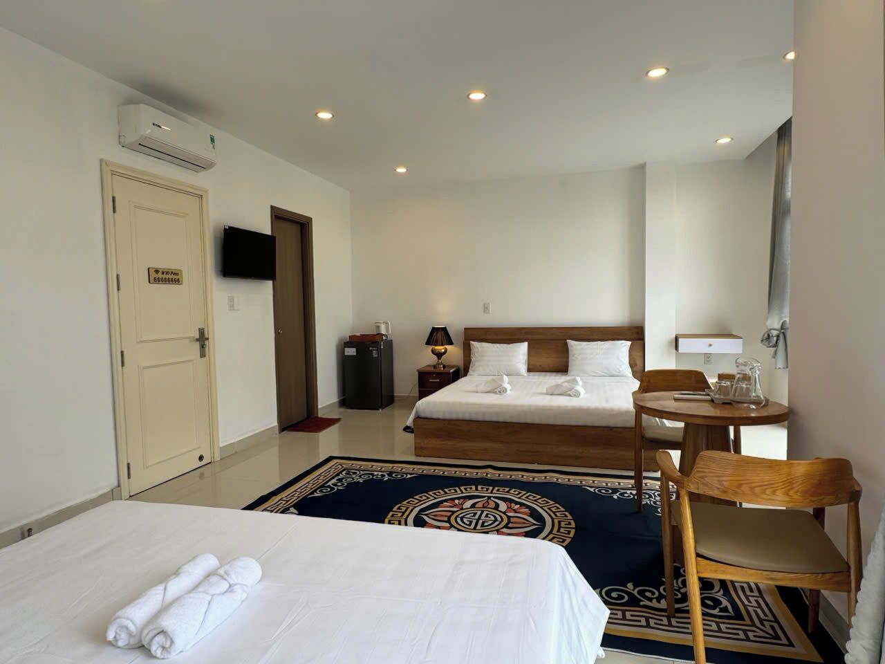 A hotel room with two beds, a desk, a chair, a TV, and a minibar.