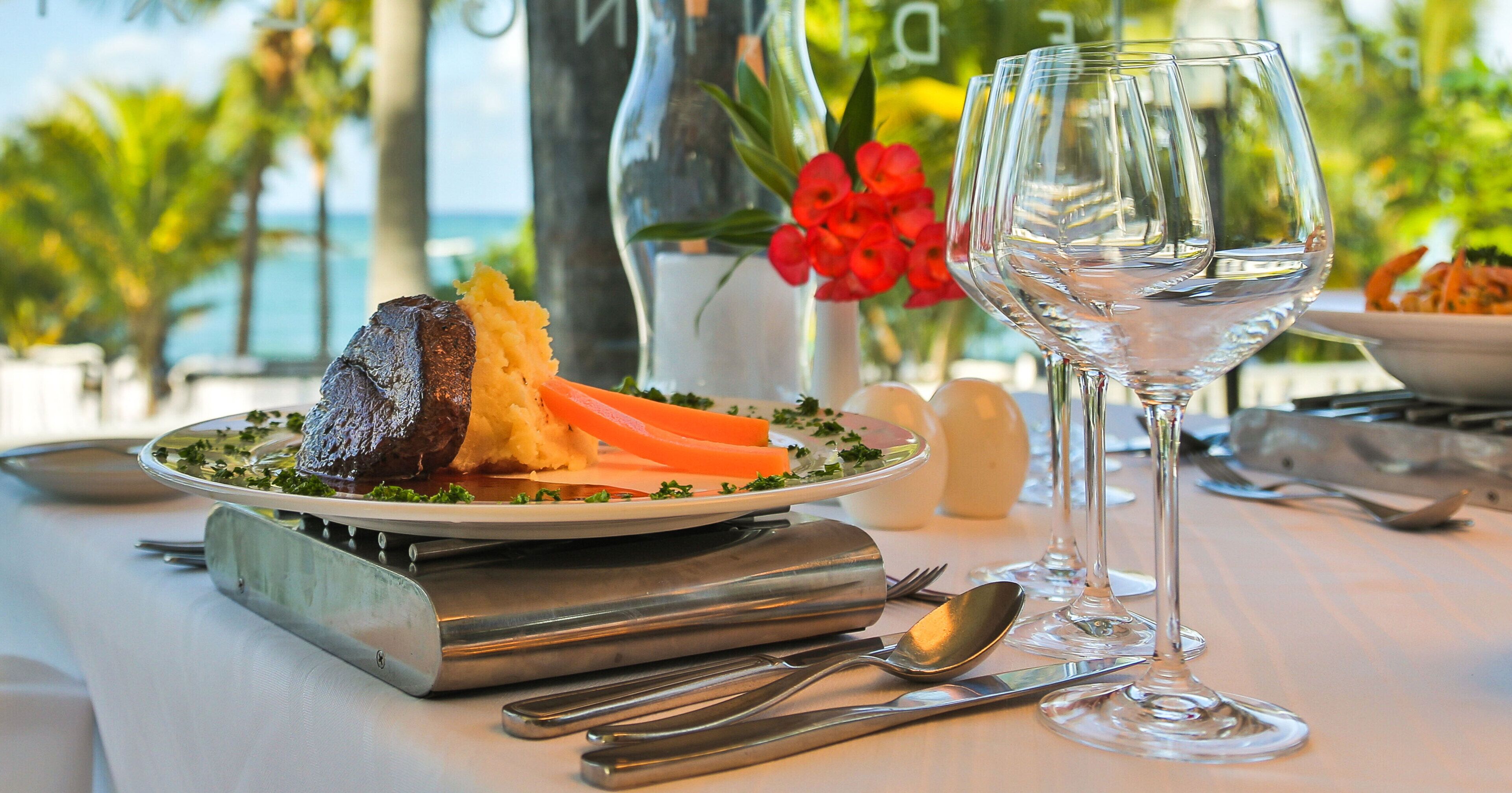 A table set with a plate of food, a wine glass, and dining utensils.