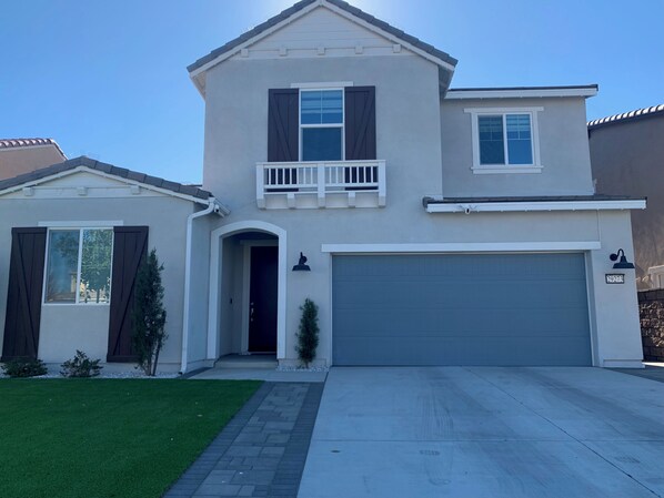 A two-story house with a garage, a small porch, and a mailbox.
