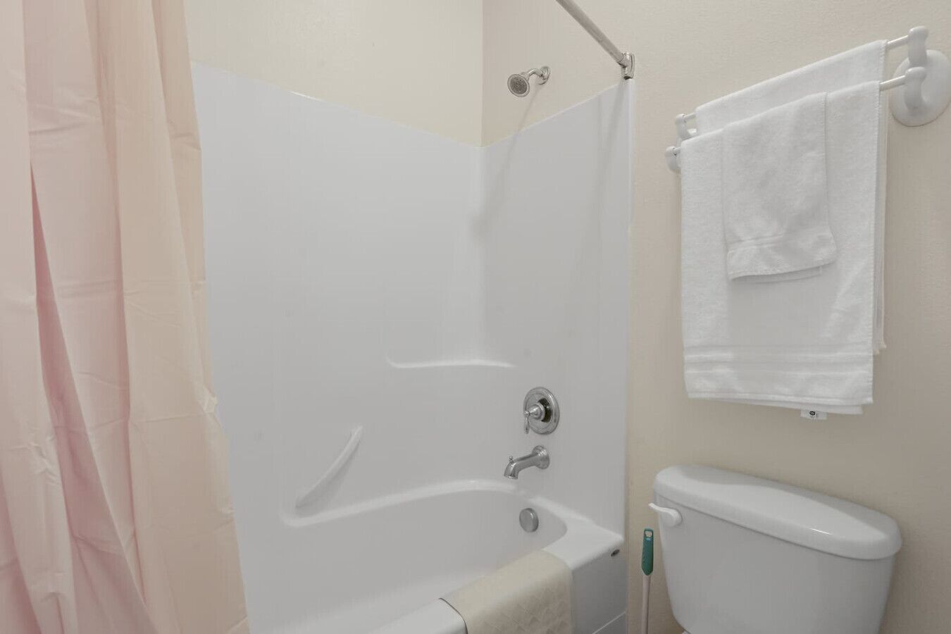 A bathroom with a bathtub, toilet, and a towel rack.