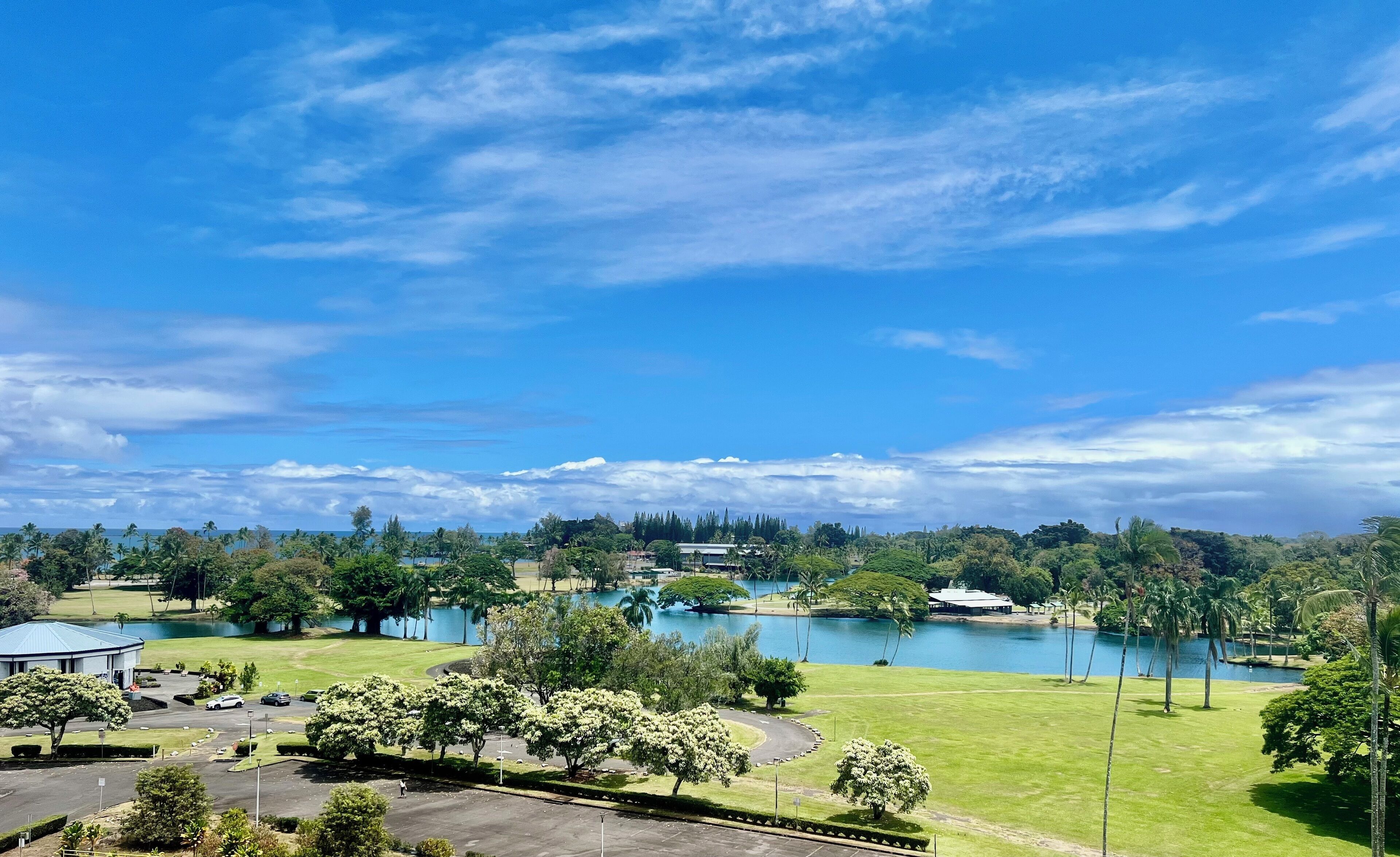A golf course with multiple ponds, surrounded by lush greenery and a clear blue sky.