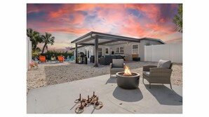 A modern outdoor patio with a fire pit, seating, and a covered area. - Oasis Paradise/Pool/Mini Golf/Exquisite Escape Sunset/Centric (Port Charlotte)