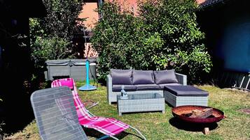 A backyard with a lounge chair, a sofa, and a coffee table.