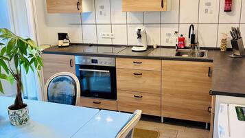 A modern kitchen with wooden cabinets, a built-in oven, a coffee maker, and a sink.