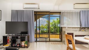 A modern living room with a flat-screen TV, a coffee table, and a dining area with a table and chairs. - Studio Apt. Just 5-mins Walk from Flamingo Beach! (Playa Flamingo)
