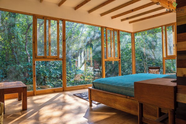 A bedroom with a large window, a bed, a bedside table, and a chair. - Agarthi (Cintalapa)