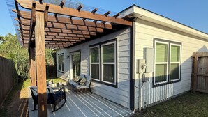 Et etplanshus med en overdækket terrasse, en skydedør og en lukket have.