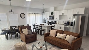 A modern living room with a brown sofa, a glass coffee table, and a dining area with a dark wooden table and chairs. - Newly built,private,and cozy. 6 guest • 3 bedrooms • 3 beds • 2 baths (Houston)