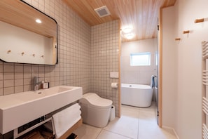 A modern bathroom with a white sink, toilet, and bathtub. - Bonbori (Nozawaonsen)