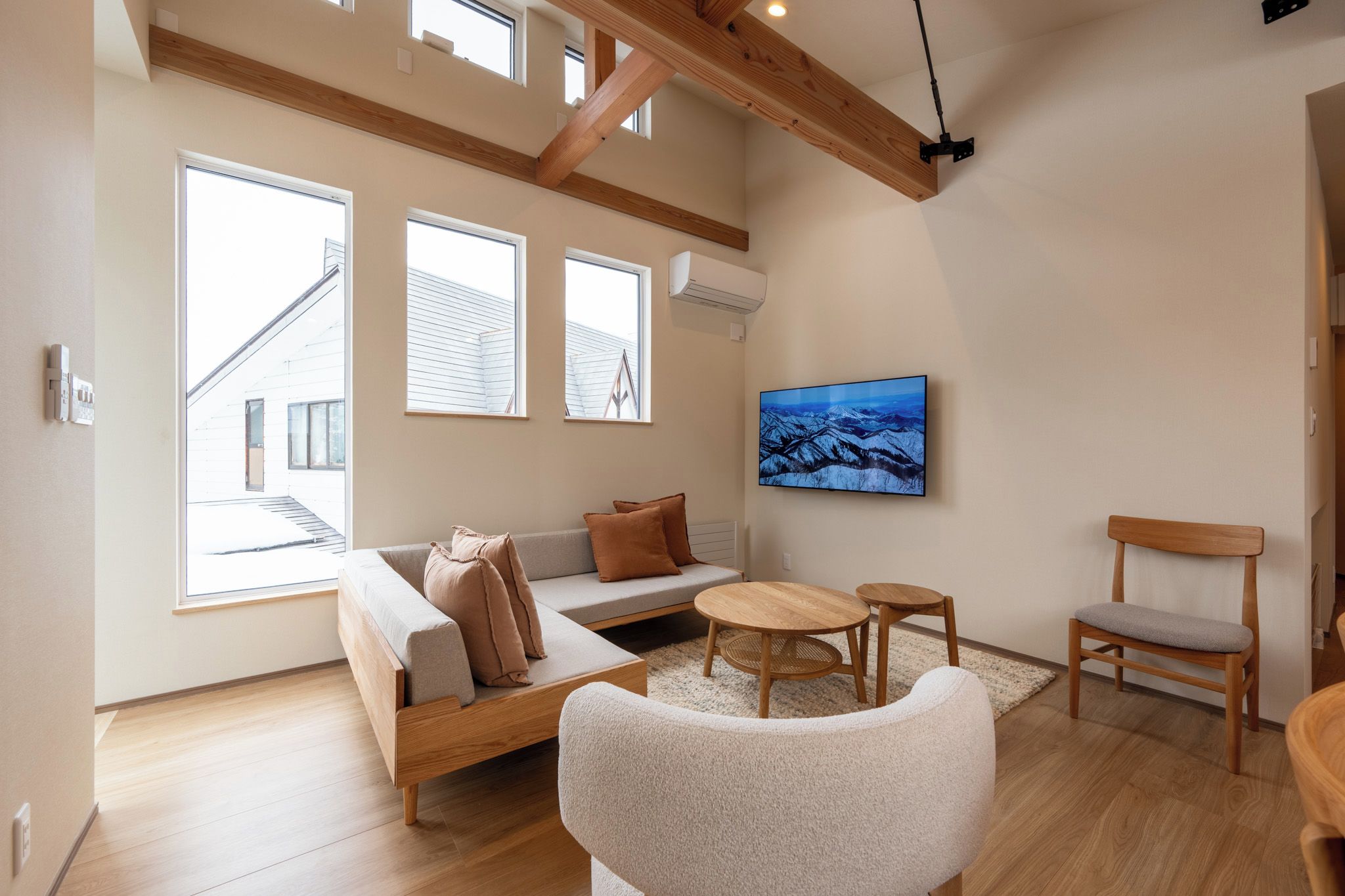 A modern living room with a sofa, two chairs, a coffee table, and a painting on the wall.