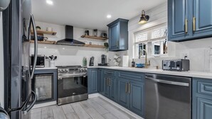 A modern kitchen with blue cabinets, stainless steel appliances, and a wooden floor. - Unique 4bedrooms 2 bathrooms stunning getaway unit (Methuen)