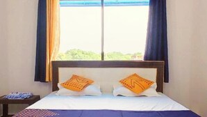 A bed with a wooden frame, two pillows, and a blue and white bedspread. - Hotel MP Katra (Katra)