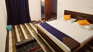 A bedroom with a bed, a ceiling fan, a window with curtains, a wooden floor, and a small rug. - Hotel MP Katra (Katra)