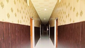 A long, narrow hallway with patterned wallpaper and dark wood paneling on the walls. - Hotel MP Katra (Katra)