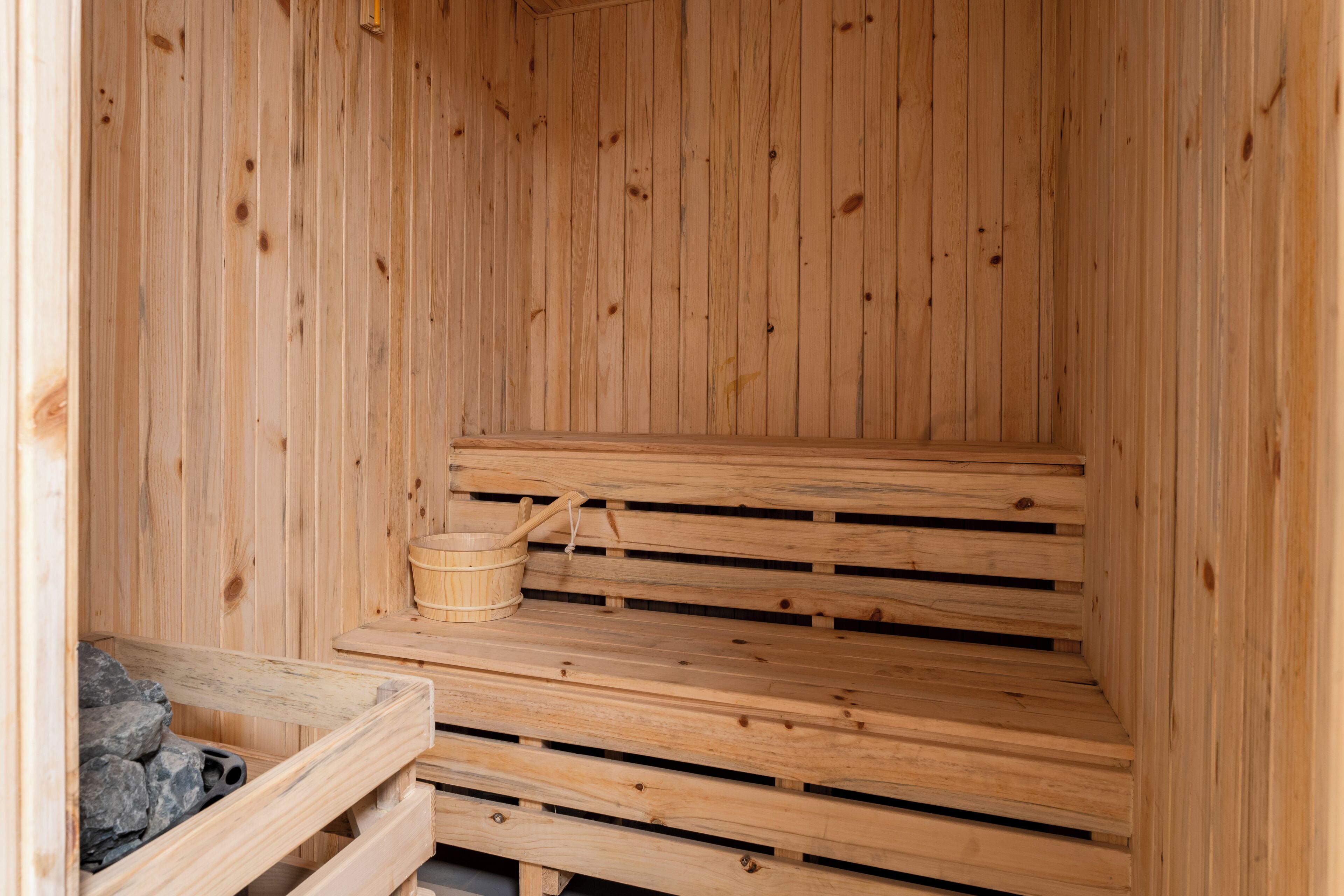 A wooden sauna with benches and a stone bench.