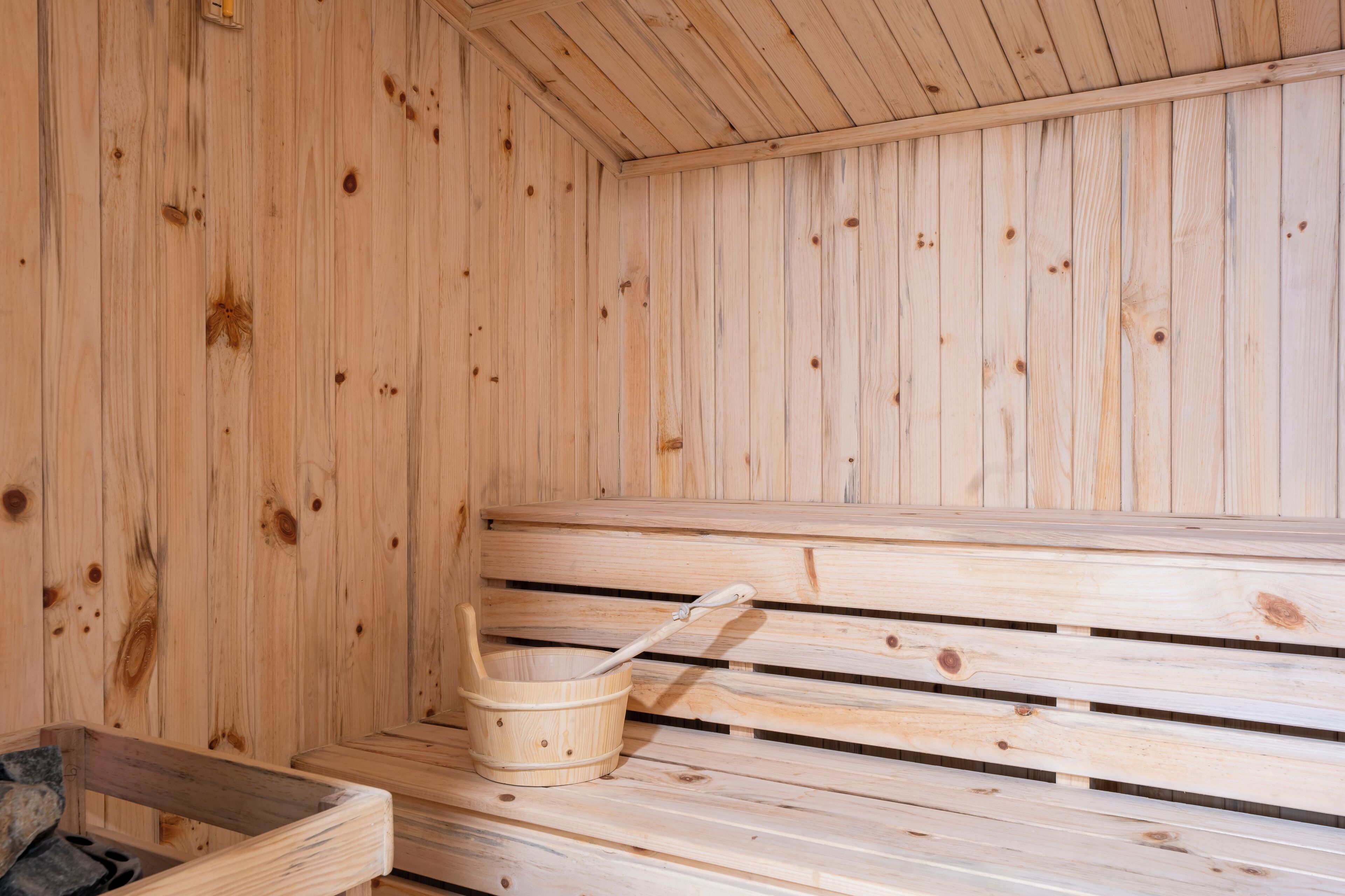 A wooden sauna with benches and a wooden bucket.