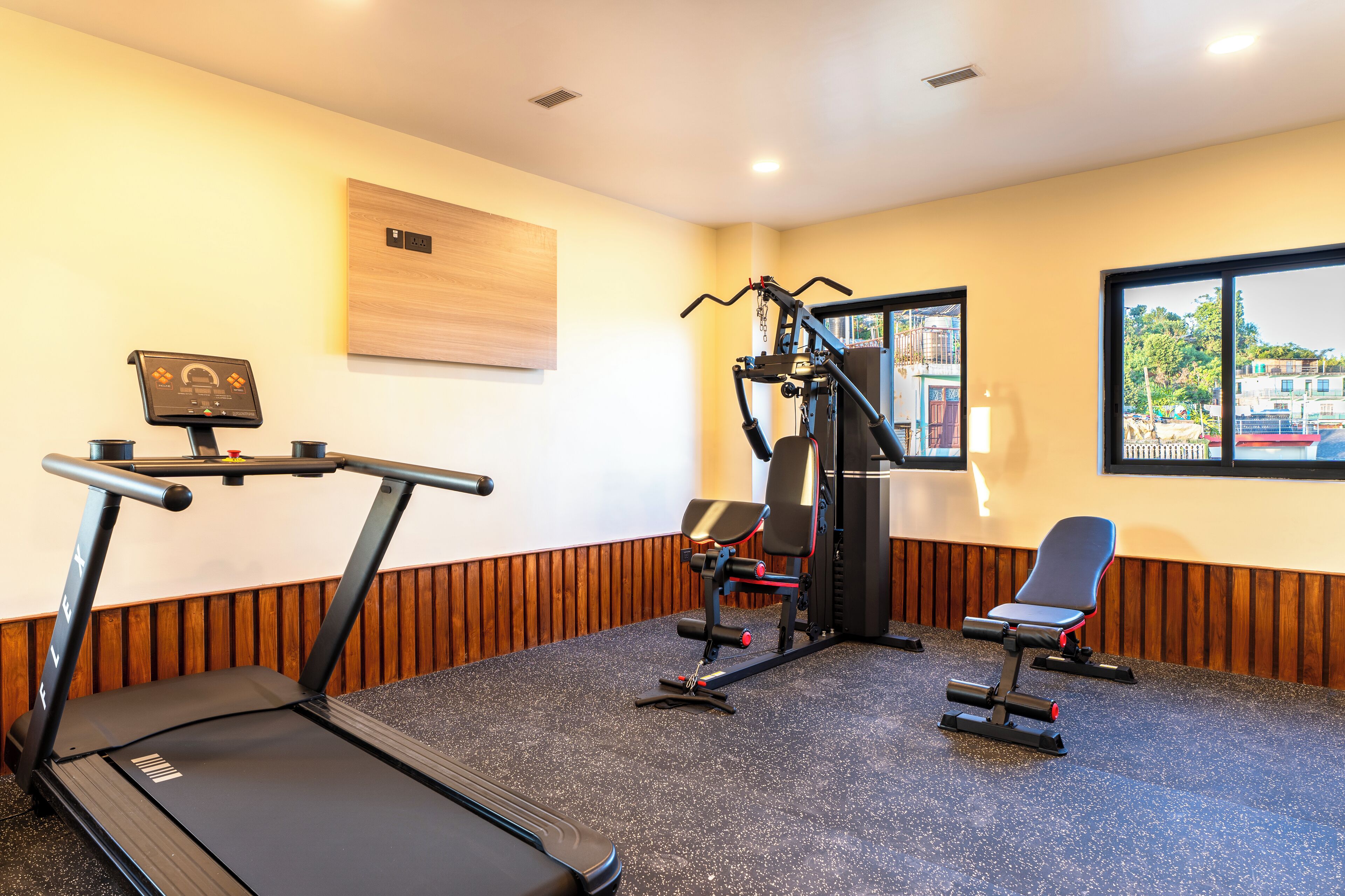 A gym with a treadmill, weight machine, and bench.