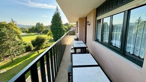 Un balcón con vistas a un paisaje verde y edificios lejanos.