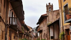 Una calle estrecha flanqueada por edificios históricos, incluyendo una imponente torre campanario.