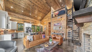 A spacious living area with a high ceiling, wooden walls, a fireplace, and a cozy seating arrangement. - Cab'n America - Pets/ Giant Jenga/ Hot tub/ Fire Pit/ Horseshoes (Broken Bow)